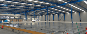 Indoor concrete slab under construction with steel framework and curing area, no workers visible.
